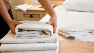 Maid placing fresh washed towels on a bed